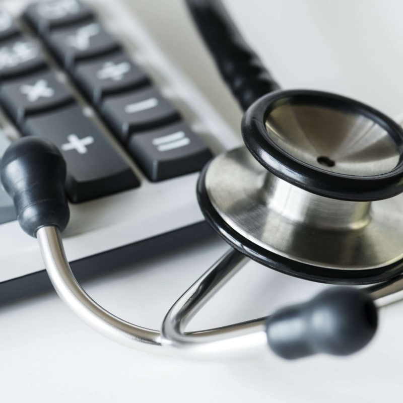 Closeup of a calculator and a stethoscope healthcare and expenses concept Closeup of a calculator and a stethoscope healthcare and expenses concept